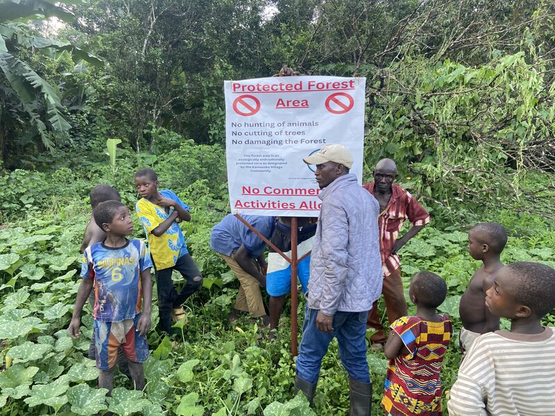 Community members gathered around a Protected Forest Area signboard designated by the Kamasoko Village Community