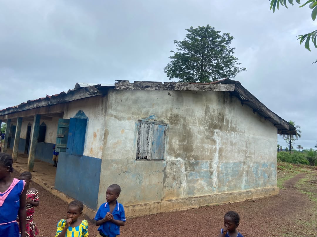 A community school building in Kambia District, Sierra Leone, with pupils gathered outside